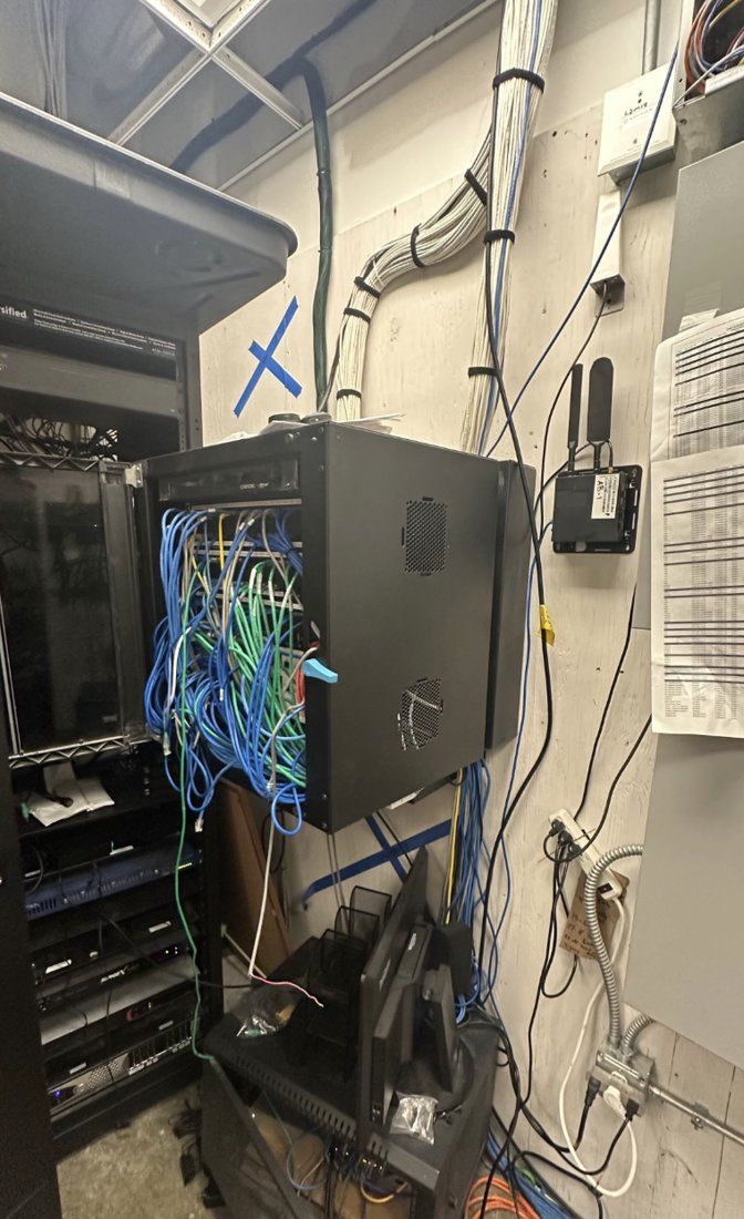 Before: overfilled wall-mount network cabinet with loose cabling