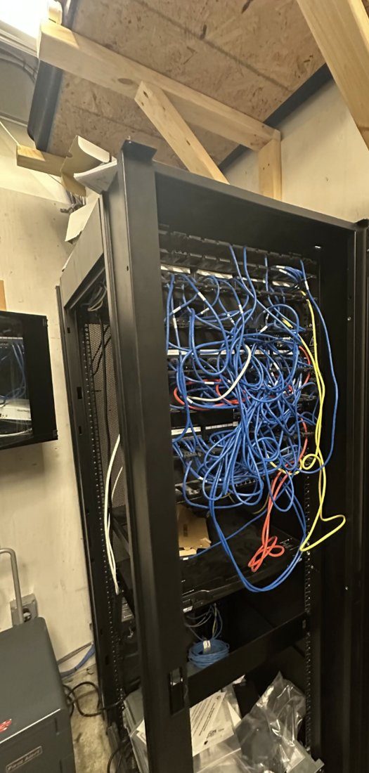 Before: tangled blue patch cables spilling out of an overfilled network equipment cabinet